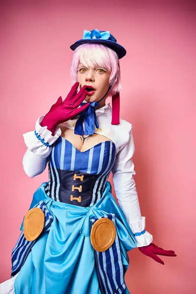 Schockierte hübsche Frau mit blauer Mütze und roten Handschuhen cosplaying anime Charakter und Blick in die Kamera — Stockfoto