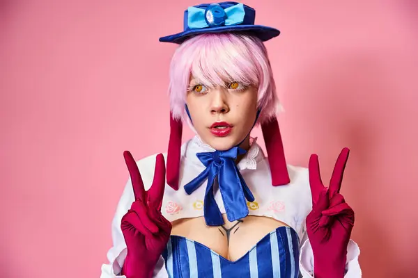 Encantadora mujer sexy cosplaying vibrante personaje de anime y mostrando gesto de paz en el telón de fondo rosa - foto de stock
