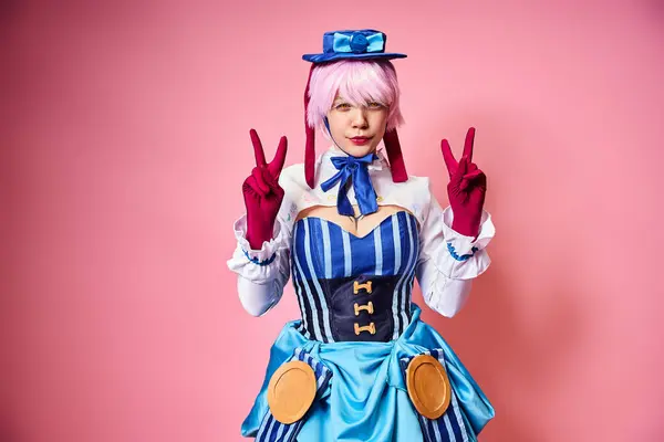Beautiful chic female cosplayer showing peace gesture and looking at camera on pink backdrop — Stock Photo