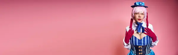 Seducente cosplayer femminile in cappello blu e abito vivace guardando la fotocamera su sfondo rosa, banner — Foto stock