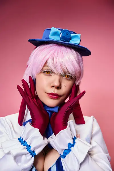 Attraente cosplayer femminile chic in cappello blu e abito vivace guardando la fotocamera su sfondo rosa — Foto stock