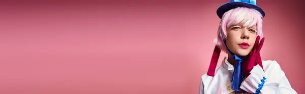 Ansprechender schicker Cosplayer mit blauem Hut und lebendigem Kleid, der auf rosa Hintergrund in die Kamera blickt, Banner — Stockfoto