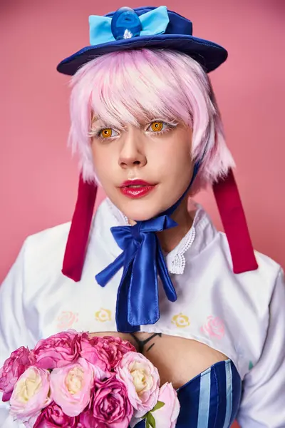 Cosplayer femminile alla moda in abiti vivaci che tengono fiori rosa e distolgono lo sguardo sullo sfondo rosa — Foto stock