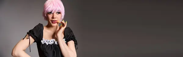 Atractiva mujer cosplaying personaje de anime con el pelo rosa y mirando hacia otro lado en el fondo gris, bandera - foto de stock