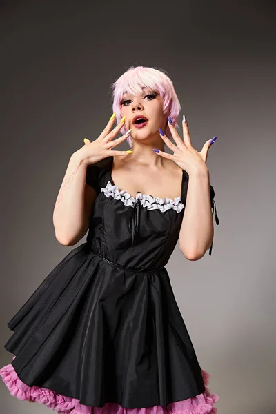 Привлекательная шикарная женщина в черном платье с розовыми волосами косплер персонаж аниме и смотреть в камеру — стоковое фото