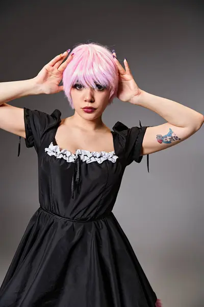 Ansprechende schicke Frau in schwarzem Kleid mit rosa Haaren, die Anime-Charakter spielt und in die Kamera schaut — Stockfoto