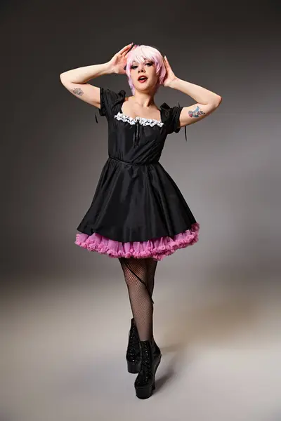 Приваблива шикарна жінка в чорній сукні з рожевим волоссям, що займається аніме персонажем і дивиться на камеру — Stock Photo
