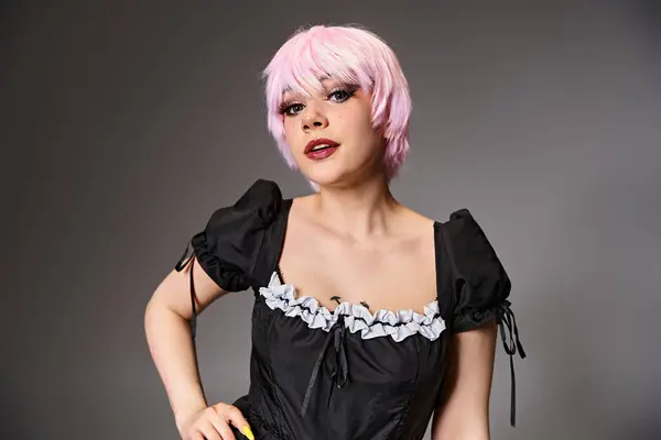 Grazioso cosplayer seducente in costume da cameriera sexy con i capelli rosa guardando la fotocamera su sfondo grigio — Foto stock
