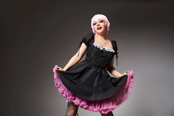 Ziemlich ansprechender Cosplayer im sexy Dienstmädchenkostüm mit rosa Haaren, der vor grauem Hintergrund in die Kamera schaut — Stockfoto