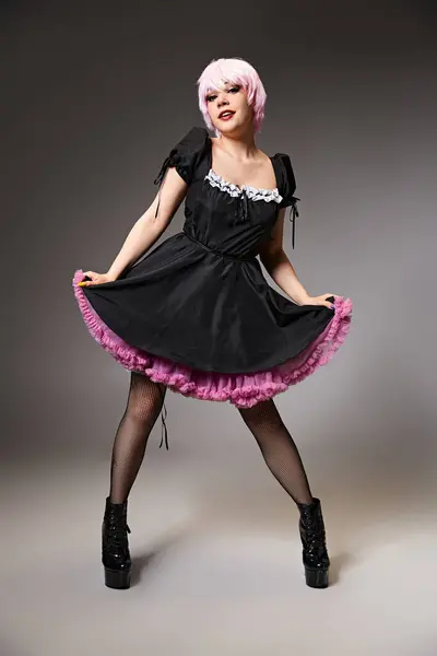 Attraktiver Cosplayer im sexy Dienstmädchenkostüm mit rosafarbenen Haaren, der vor grauem Hintergrund in die Kamera blickt — Stockfoto
