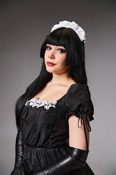 Luscious sexy female cosplayer in tempting maid costume looking at camera on gray background — Stock Photo