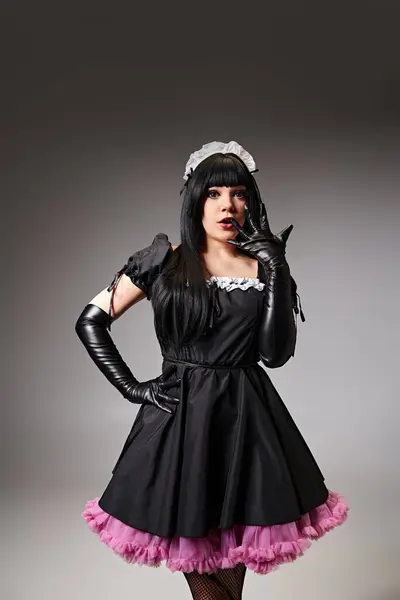 Appealing shocked cosplayer in sexy maid costume gesturing and looking at camera on gray backdrop — Stock Photo
