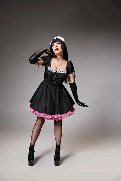 Good looking young cosplayer in maid costume posing alluringly and looking away on gray backdrop — Stock Photo
