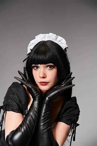 Attractive sexy female cosplayer in tempting maid costume looking at camera on gray background — Stock Photo