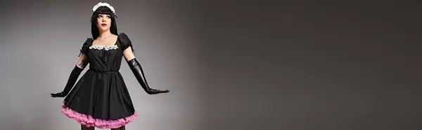 Сексуальна красива жінка в чорному костюмі покоївки, що грає і дивиться на сірий фон, банер — стокове фото