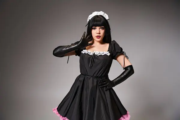 Enticing sexy female cosplayer in tempting maid costume looking at camera on gray background — Stock Photo