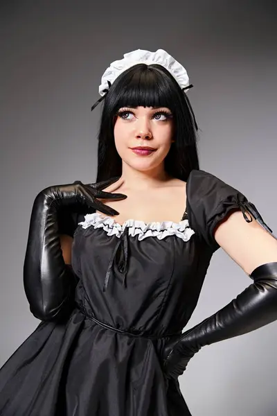 Sexy cosplayer atractivo en traje de criada posando seductor y mirando hacia otro lado en el fondo gris - foto de stock