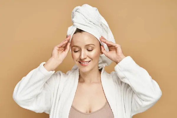 Una bella donna con un asciugamano elegantemente avvolto intorno alla testa, trasudando un senso di relax e cura di sé. — Foto stock