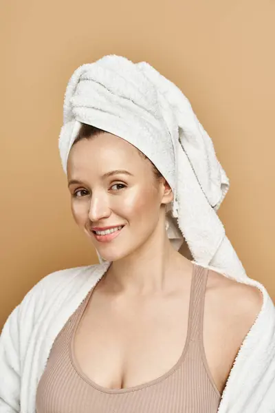 Eine attraktive Frau mit natürlicher Schönheit, die ein weiches Handtuch auf dem Kopf trägt, wirkt gelassen und entspannt. — Stockfoto
