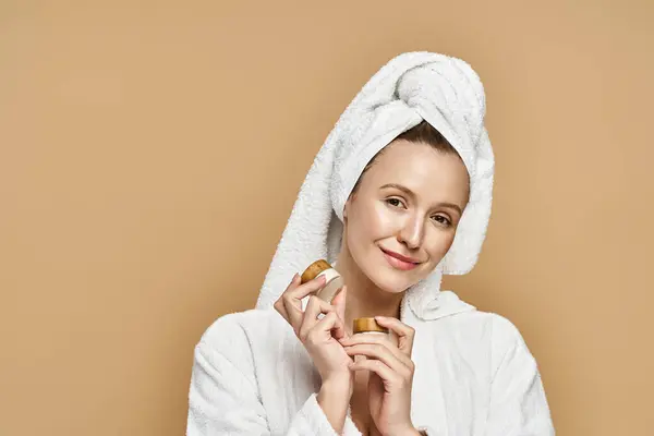 Una belleza natural sostiene una pastelería con una toalla elegantemente cubierta sobre su cabeza, encarnando creatividad y elegancia. - foto de stock