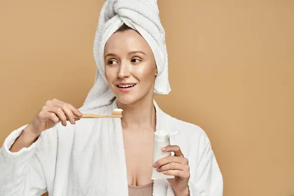 Eine attraktive Frau mit Handtuch auf dem Kopf putzt sich aktiv die Zähne. — Stockfoto