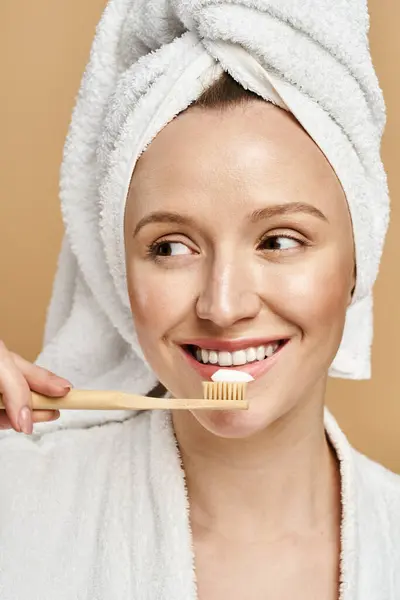 Una donna di bellezza naturale si lava attivamente i denti mentre indossa un asciugamano sulla testa. — Foto stock