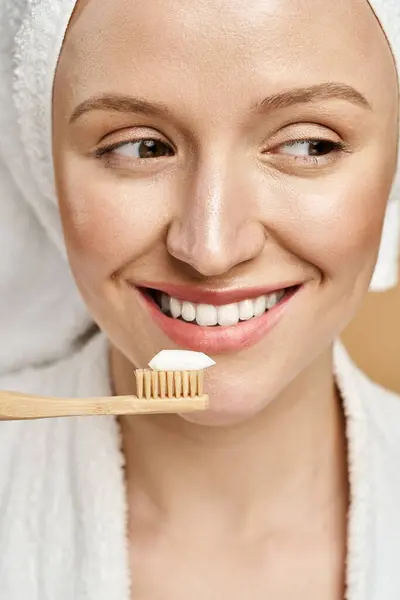Eine natürliche Schönheit in Aktion, die ein Handtuch auf dem Kopf balanciert, während sie eine Zahnbürste im Mund hält. — Stockfoto