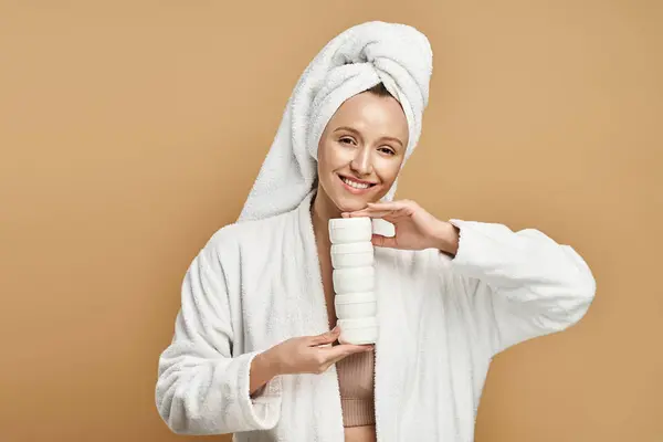 Una mujer elegante con una túnica blanca sostiene serenamente la crema, encarnando la pureza y la serenidad. - foto de stock