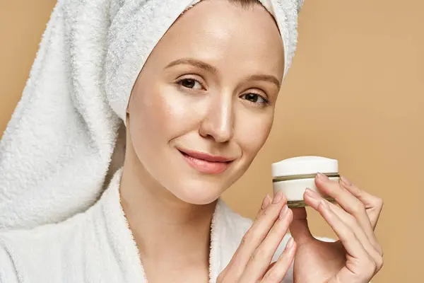 A woman with a towel on her head holds a jar of cream, embracing self-care and natural beauty. — Stock Photo