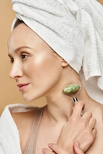 Una donna con un asciugamano avvolto intorno alla testa, in mostra la bellezza naturale e la routine di auto-cura. — Foto stock