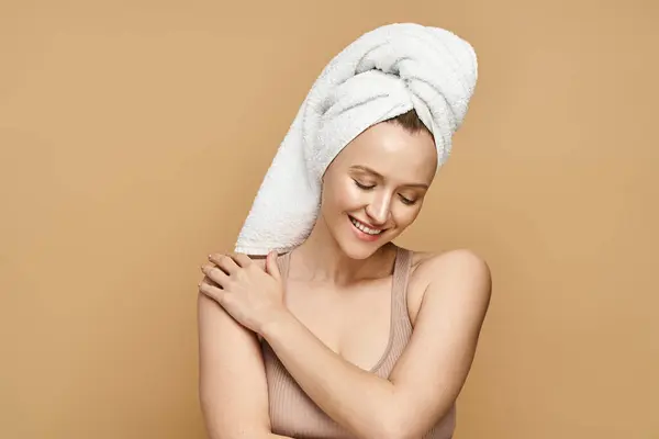 Una donna graziosa con un asciugamano in testa, che incarna bellezza e cura di sé in un momento sereno. — Foto stock