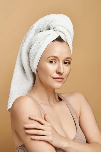 Una donna con un asciugamano elegantemente drappeggiato sulla testa, trasudando bellezza naturale ed eleganza in una posa in bilico. — Foto stock
