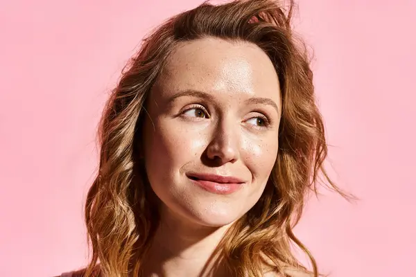Um close-up de uma mulher atraente com beleza natural, posando ativamente contra um fundo rosa vibrante. — Fotografia de Stock