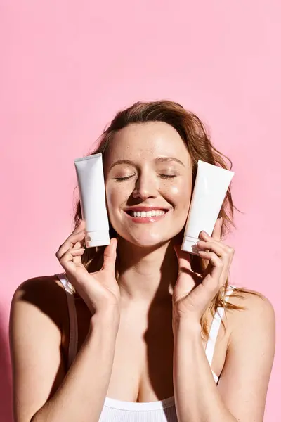 An attractive woman is playfully holding cream in front of her face, showcasing natural beauty and charisma. — Stock Photo