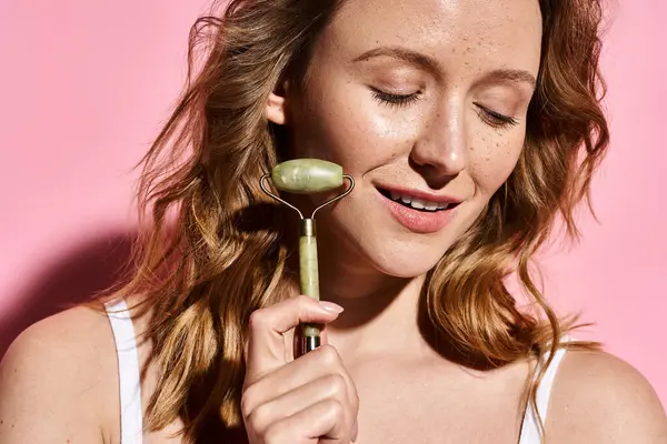 An attractive woman with natural beauty elegantly with face roller, showcasing creativity and grace. — Stock Photo