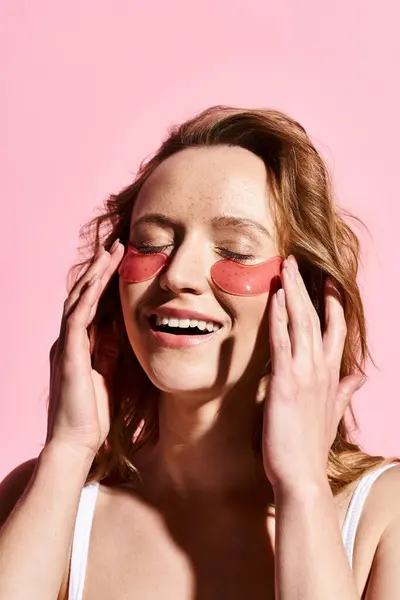 Una mujer con un par de parches en la cara, encarnando el cuidado personal y la relajación. - foto de stock