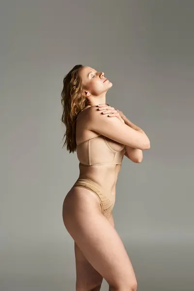 Una donna sorprendente in un body abbronzato colpisce una posa dinamica per la fotocamera, mostrando la sua grazia e bellezza. — Foto stock