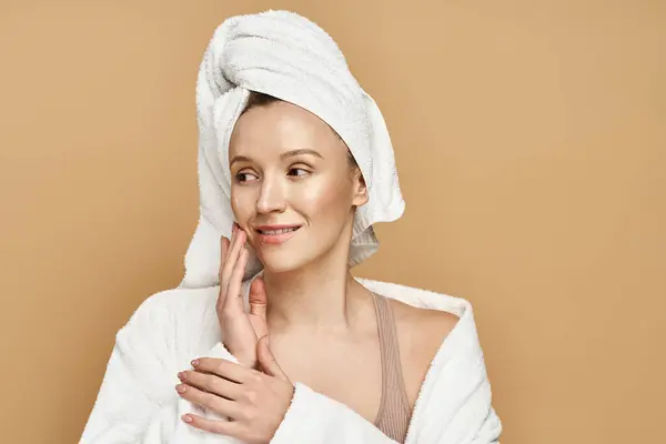 Una mujer con una toalla en la cabeza, revelando su belleza natural mientras exuda serenidad y renovación. - foto de stock