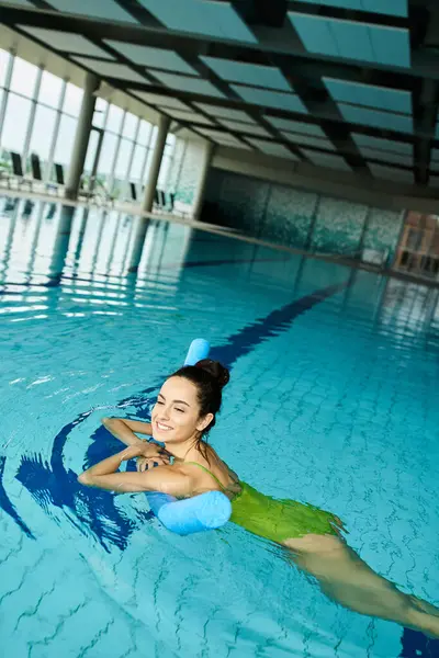A stunning brunette woman gracefully swimming in an indoor spa pool. — Stock Photo