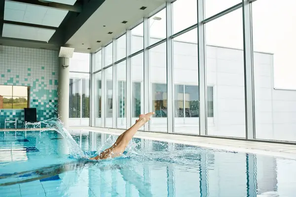 Eine Frau schwimmt anmutig in einem großen Pool, umgeben von blauem Wasser unter klarem Himmel. — Stockfoto