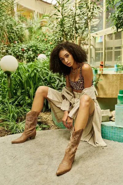 Full length of young black woman with curly hair posing in her trendy look in a botanical setting — Stock Photo