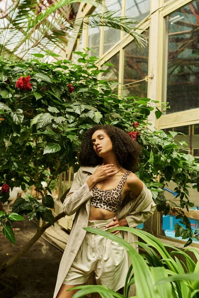 Junge Afroamerikanerin mit lockigem Haar posiert in ihrem trendigen Look in exotisch grüner Umgebung — Stockfoto