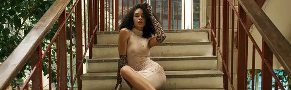 Young black woman in dress and animal print gloves sitting on stairs in urban setting, banner — Stock Photo