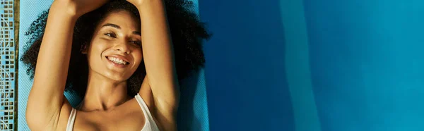 Vista superior da mulher americana africana feliz em roupa de banho deitada à beira da piscina, exalando tranquilidade, banner — Fotografia de Stock