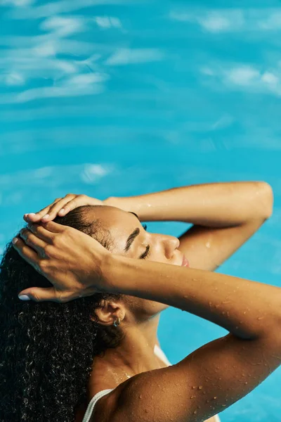 Jovem afro-americana mulher em um maiô branco encontra serenidade na água fria piscina azul — Fotografia de Stock