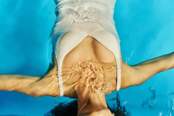 Vista dall'alto della donna africana americana ritagliata che nuota sulla schiena in acqua limpida della piscina, tranquillità — Foto stock