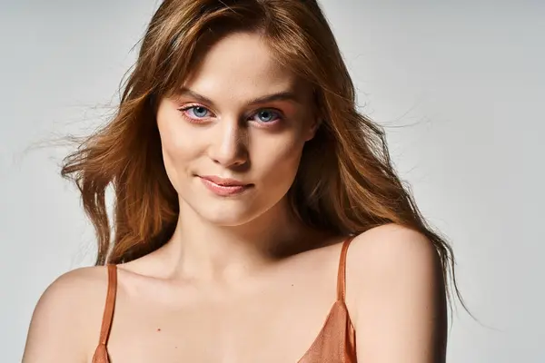 Крупним планом фото дівчини зі світлою посмішкою, персиковий натуральний макіяж з чистою шкірою на сірому фоні — стокове фото