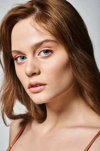 Retrato de cerca de chica atractiva con maquillaje natural melocotón con piel perfecta sobre fondo gris - foto de stock
