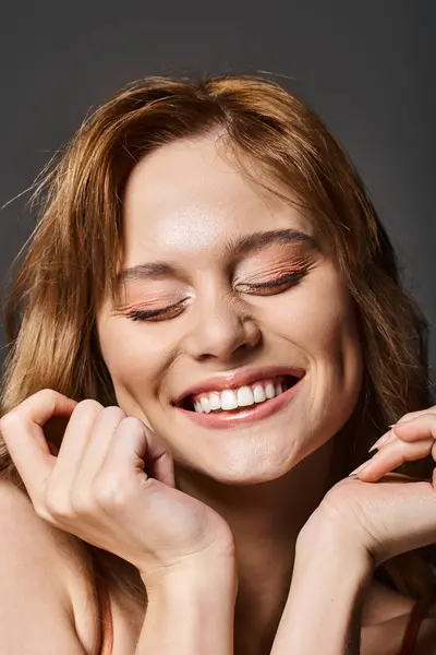 Beauty portrait of an attractive laughing young woman touching her face, posing in studio — Stock Photo