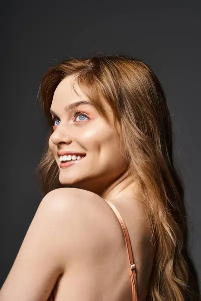 Back view portrait of cheerful smiling young woman with blue eyes, posing on dark grey background — Stock Photo